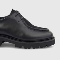Close-up of a Formales men's black leather chunky sole lace-up shoe with intricate stitching and sturdy lug sole.