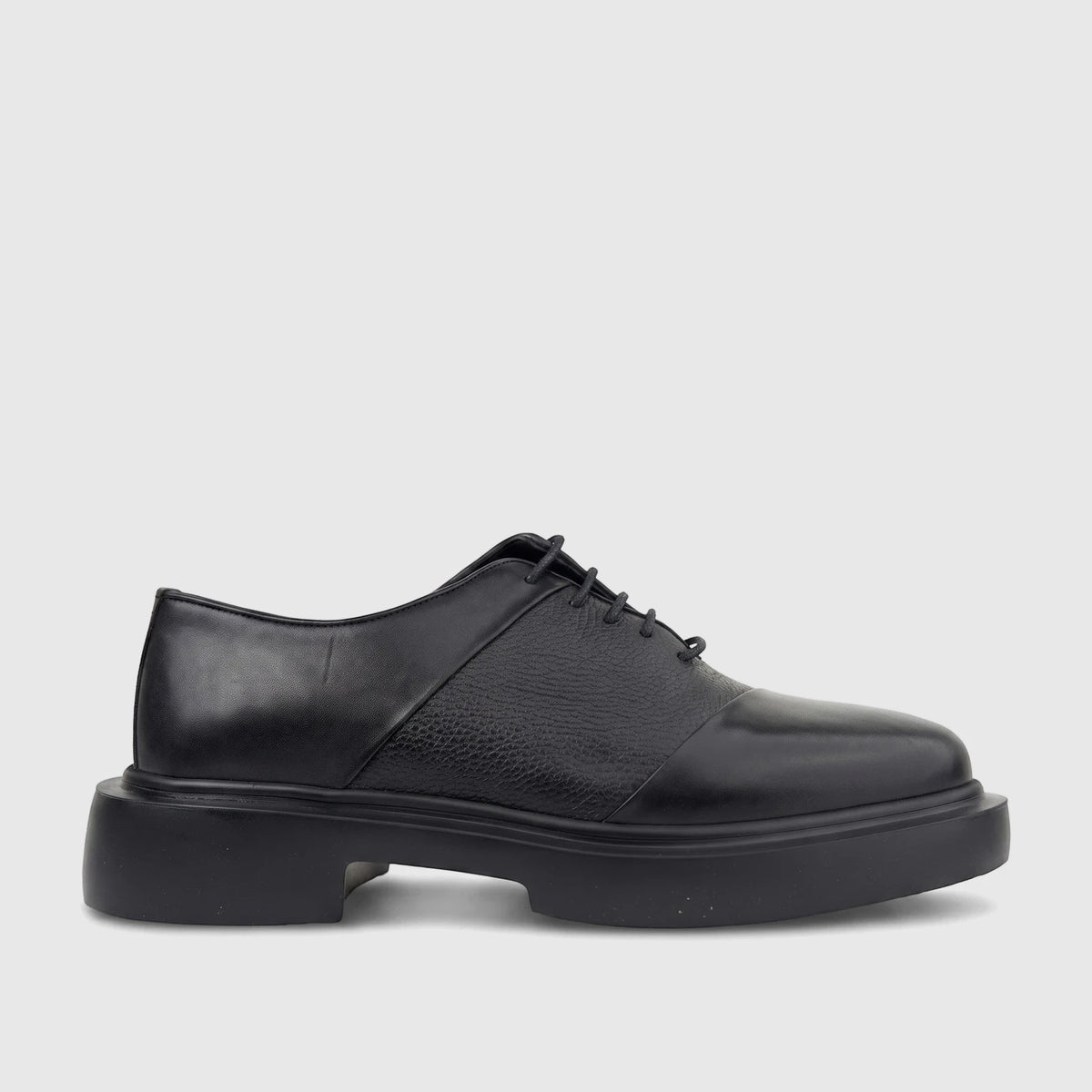 Black leather men's chunky sole lace-up shoe, shown from the side, highlighting its smooth and pebbled textures.
