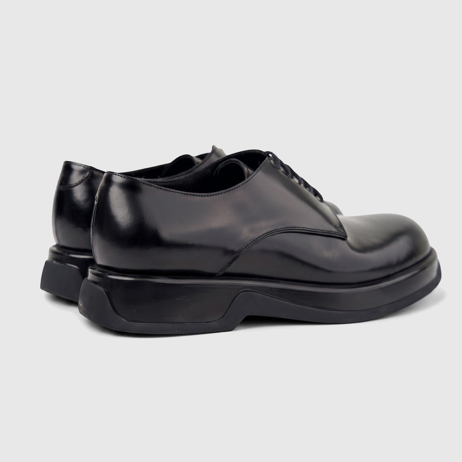 Black hi-shine leather formal shoes for men with chunky soles and lace-up design, shown from a rear side view.