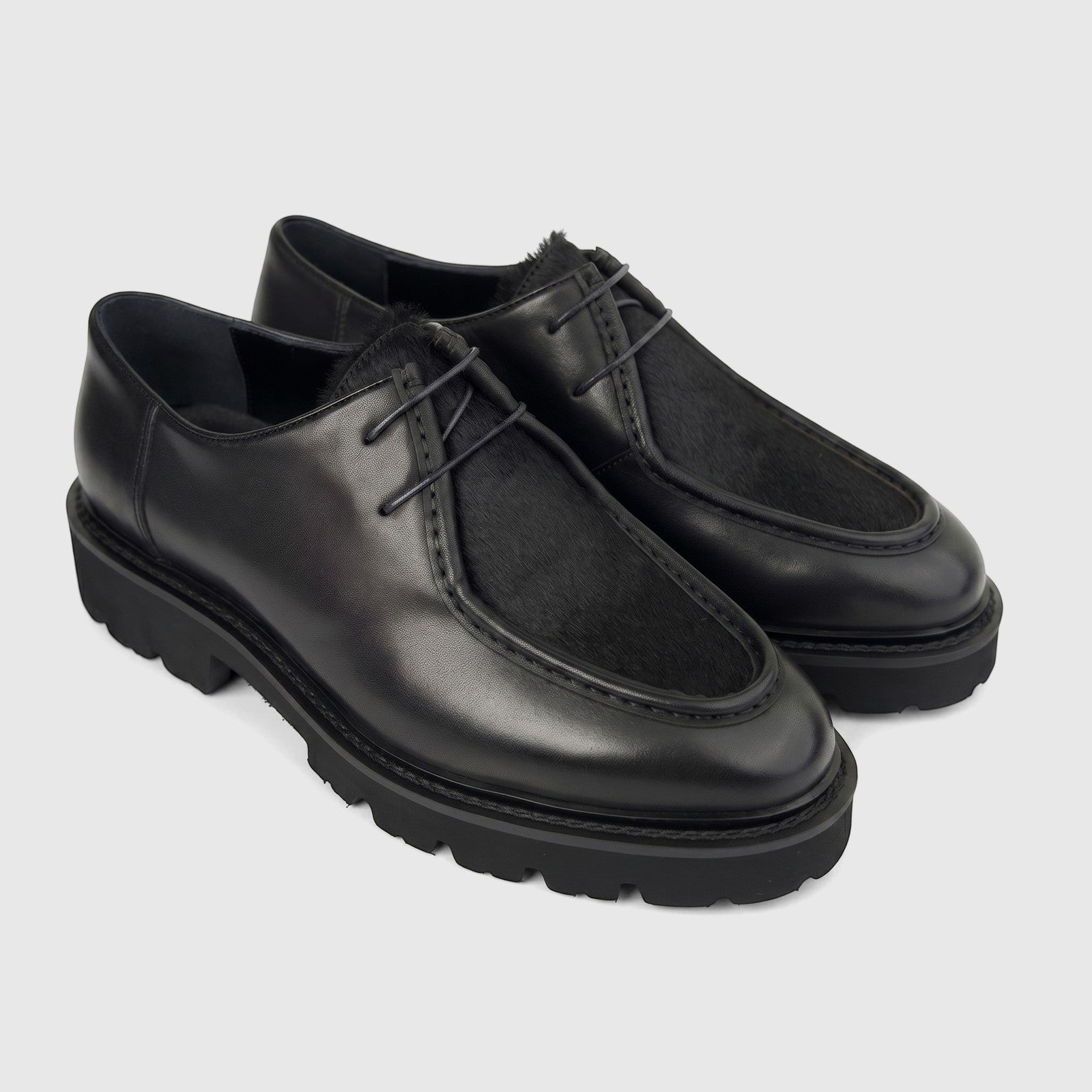 A pair of black Formales Men's Leather Chunky Sole Lace Up shoes, featuring a textured fur vamp and thick rubber soles,