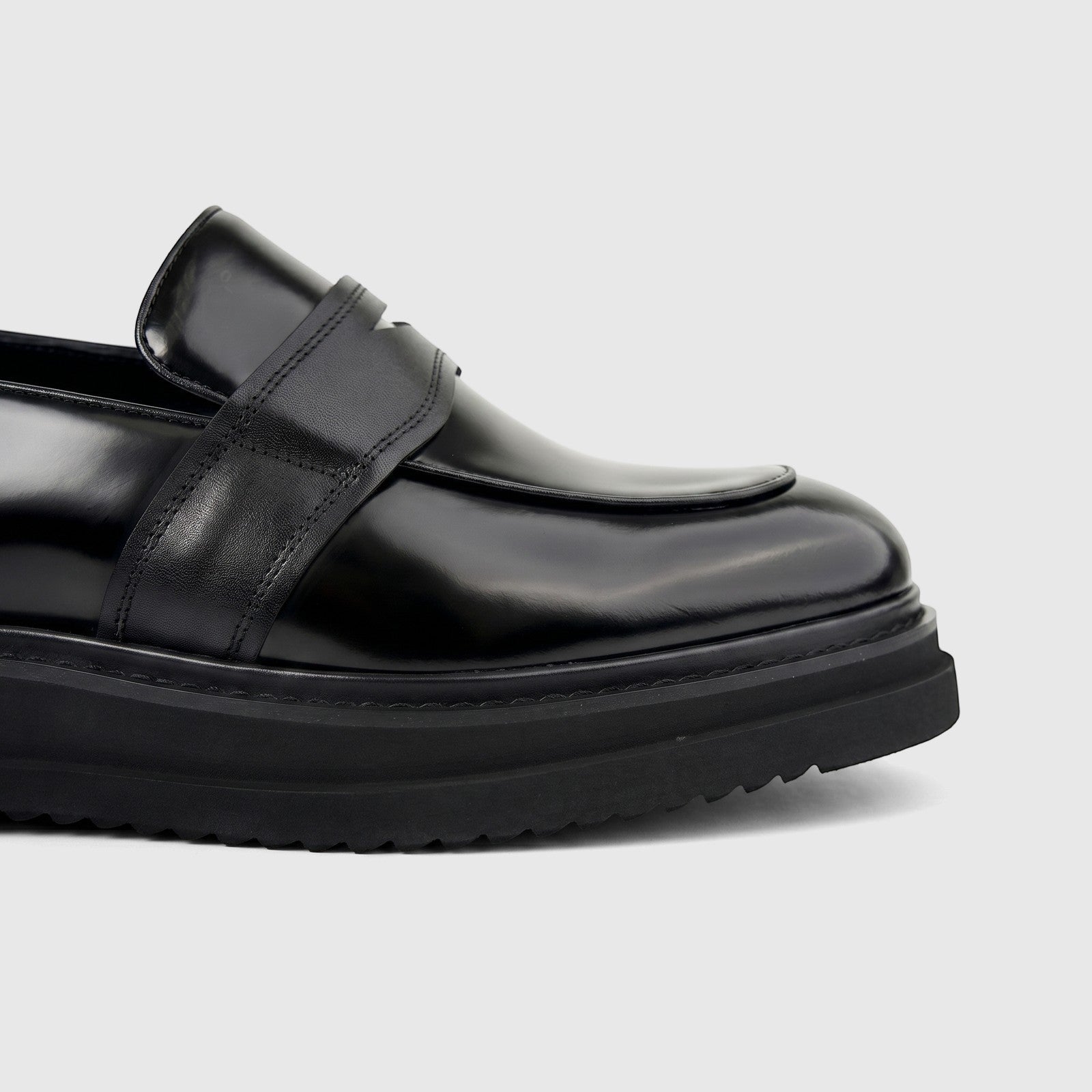 Formales Men's Leather Chunky Sole Slip On shoe in black, featuring a shiny finish and detailed penny strap, close-up side