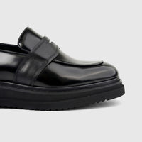 Formales Men's Leather Chunky Sole Slip On shoe in black, featuring a shiny finish and detailed penny strap, close-up side
