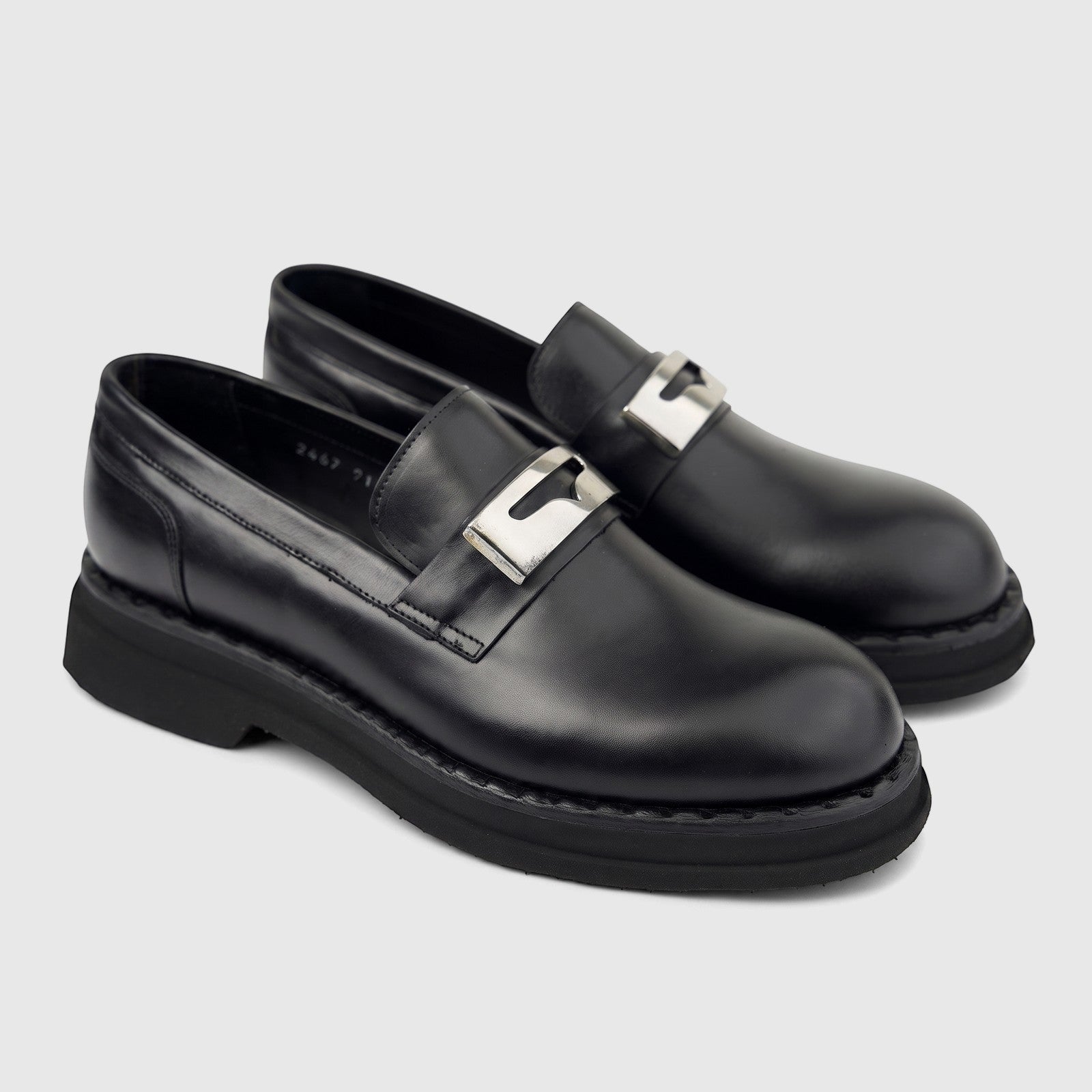 Black leather Formales men's slip-on loafers with chunky soles and silver-tone buckle details, presented at an angle.