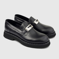 Black leather Formales men's slip-on loafers with chunky soles and silver-tone buckle details, presented at an angle.