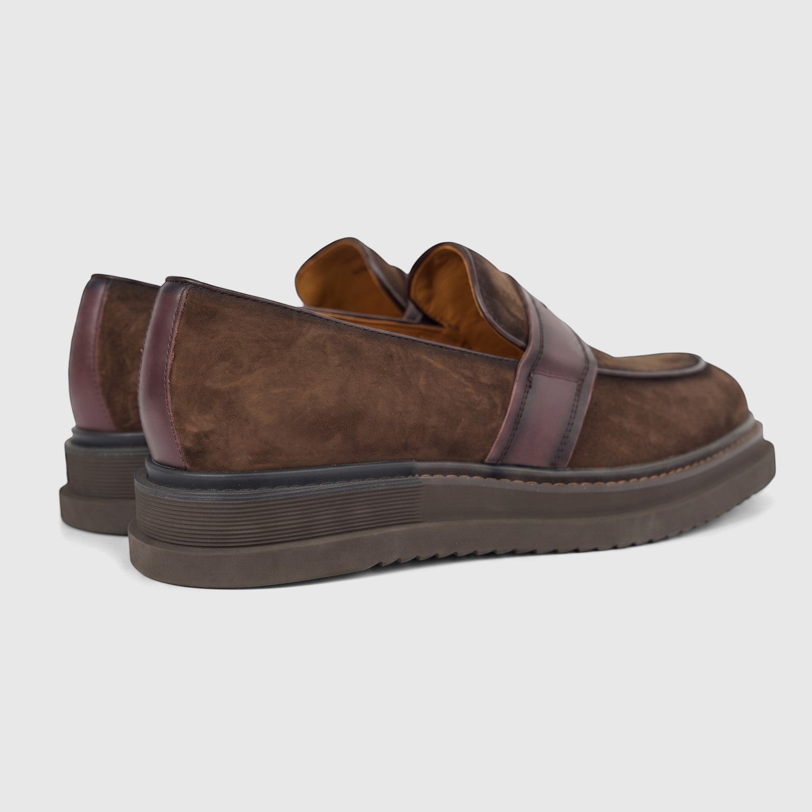 Brown suede Formales men's slip-on loafers with chunky dark soles, featuring a dark leather strap, viewed from the rear-side.