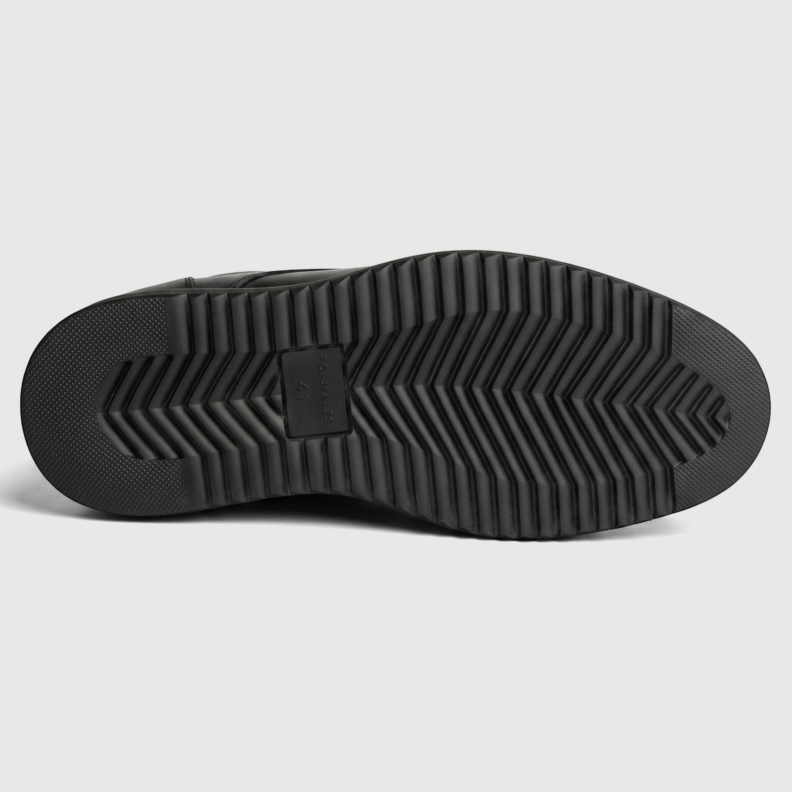 Black Formales men's slip-on shoe with a chunky rubber sole featuring a distinct zigzag tread pattern, viewed from the
