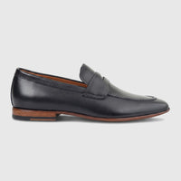 Black leather men's dress slip-on loafer shoe with a brown sole, featuring a penny strap, photographed from the side.