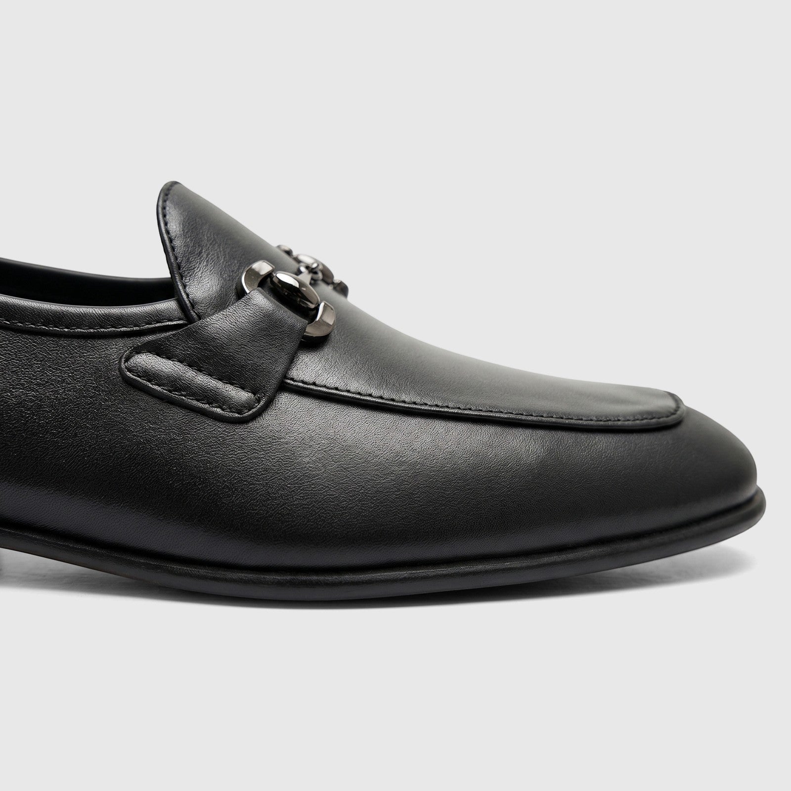 Close-up of a Formales Men's Leather Loafer in black, featuring silver-tone bit hardware on a textured leather upper.