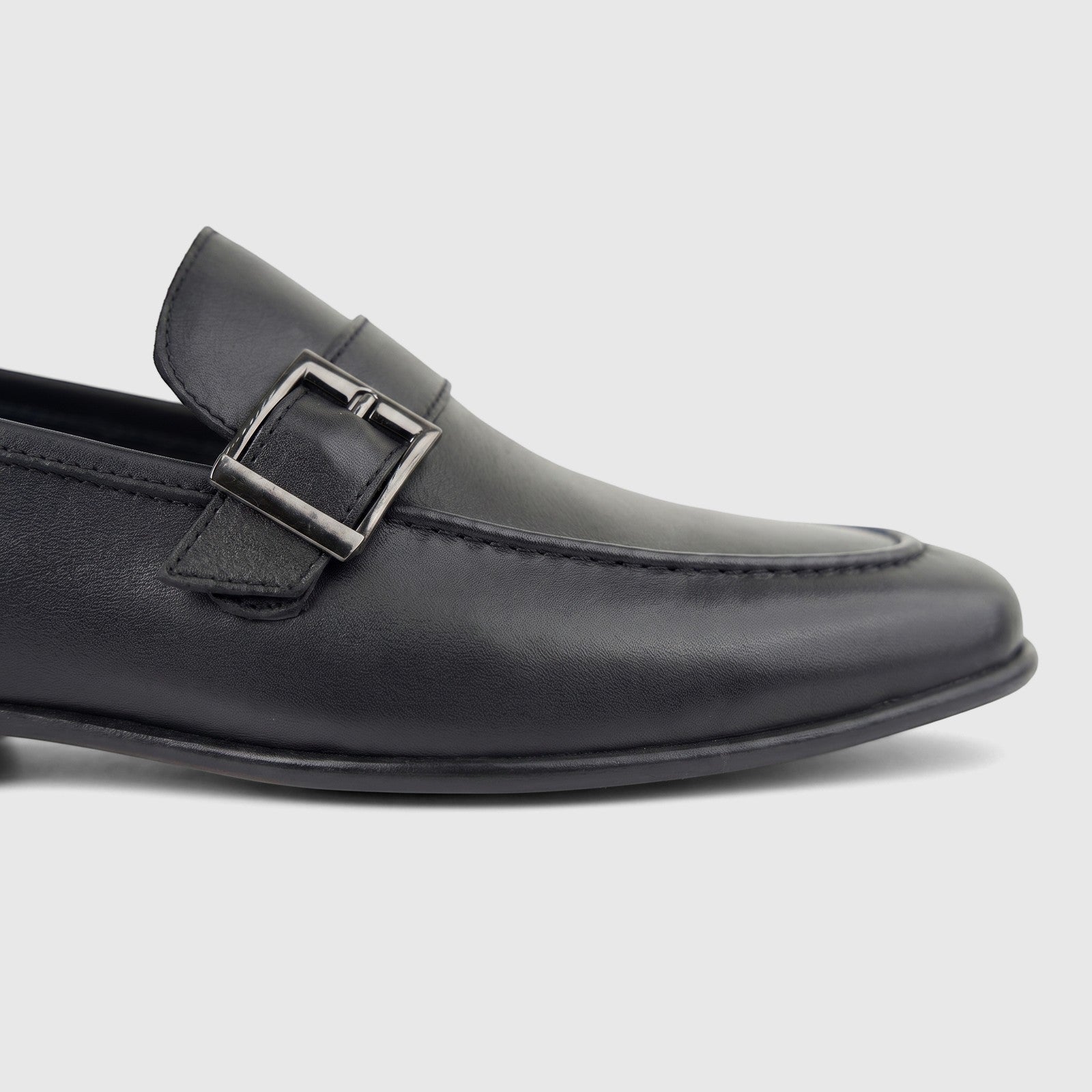 Black Formales men's leather loafer with a side buckle, shown in a close-up side view, highlighting its texture and