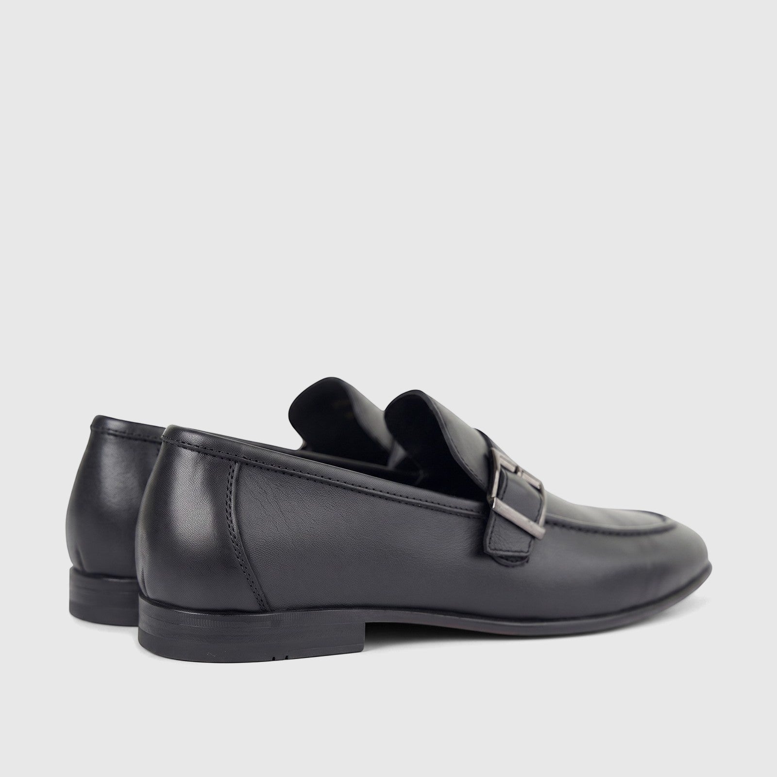 A pair of black leather men's loafers with a silver buckle detail, viewed from a side angle on a white background. Formal