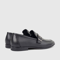 A pair of black leather men's loafers with a silver buckle detail, viewed from a side angle on a white background. Formal