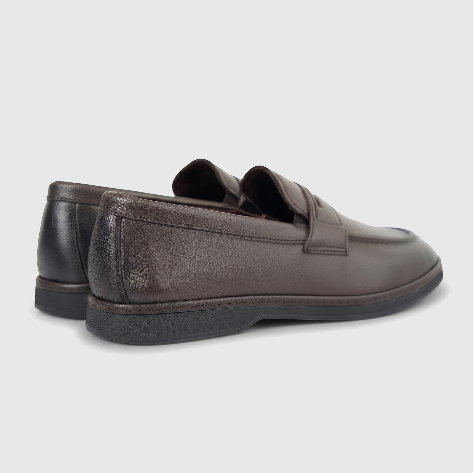 A pair of Formales men's coffee brown leather loafers with black soles, viewed from a rear-quarter angle on a white