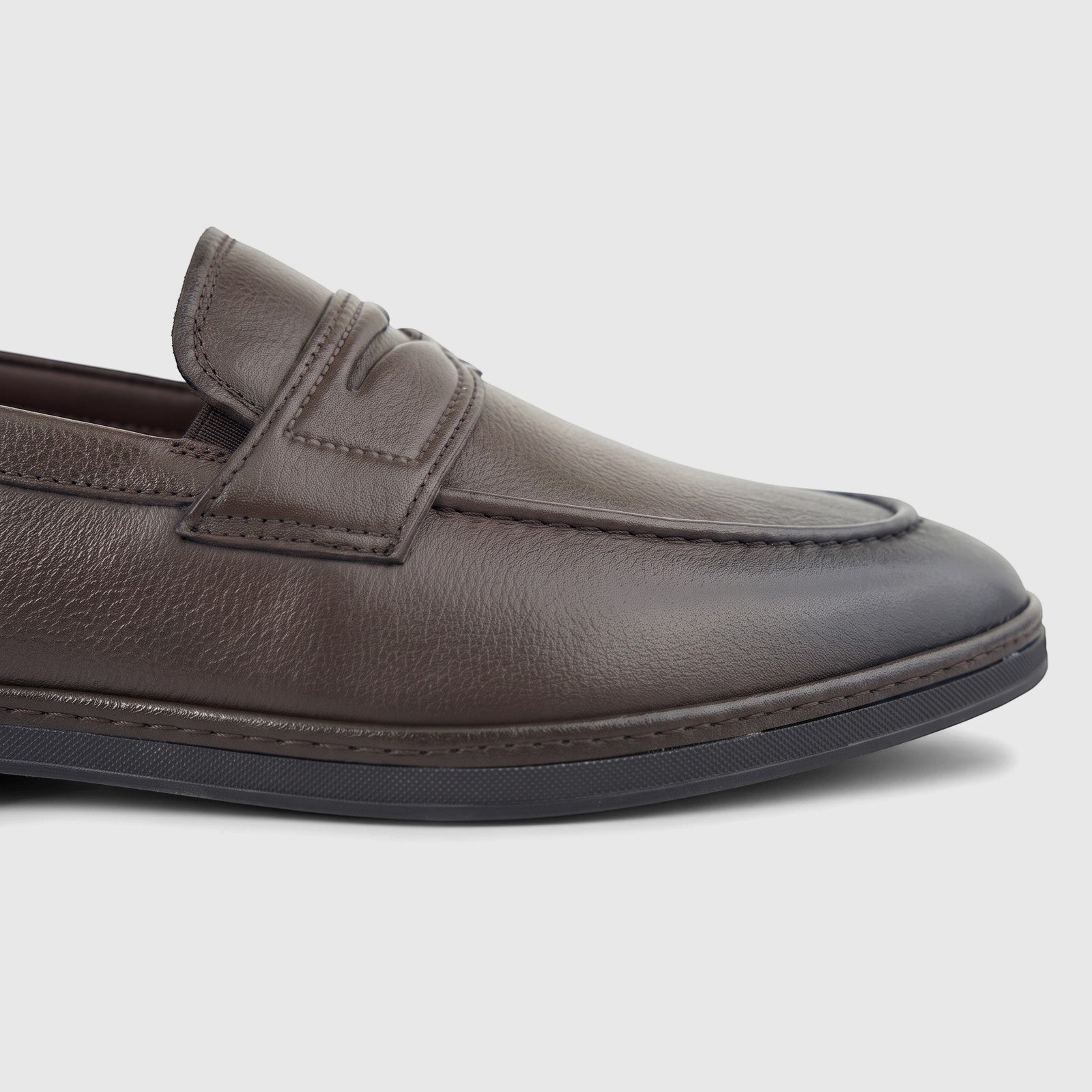 Close-up of a men's Formale leather loafer in coffee brown, featuring detailed stitching and a black sole.