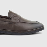 A close-up of a brown leather men's loafer from the side, showcasing its textured surface and classic design.