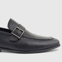 Black leather men's loafer with a sleek design and metal buckle detail, captured from a side perspective.