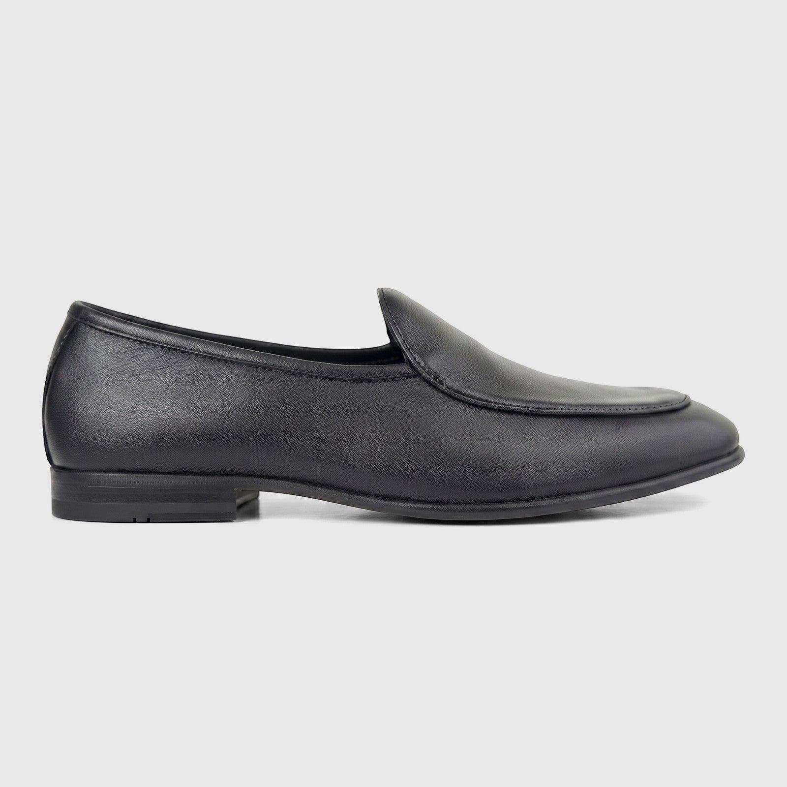 A single black leather men's loafer, seen from the side, with a low heel and clean stitching.