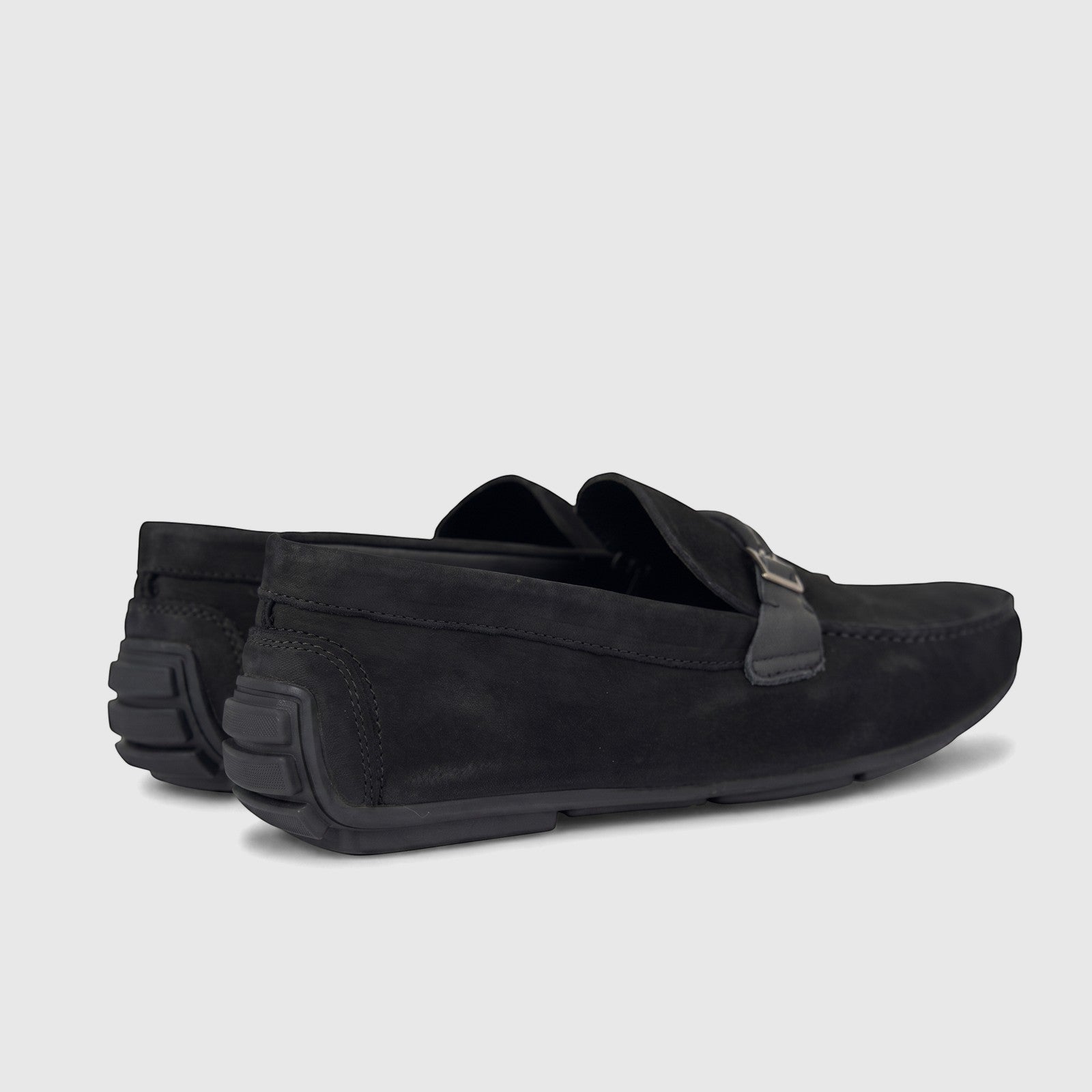 Black formal men's leather loafer shoes with a silver-tone buckle detail and textured rubber heels, side view.