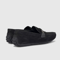 Black formal men's leather loafer shoes with a silver-tone buckle detail and textured rubber heels, side view.
