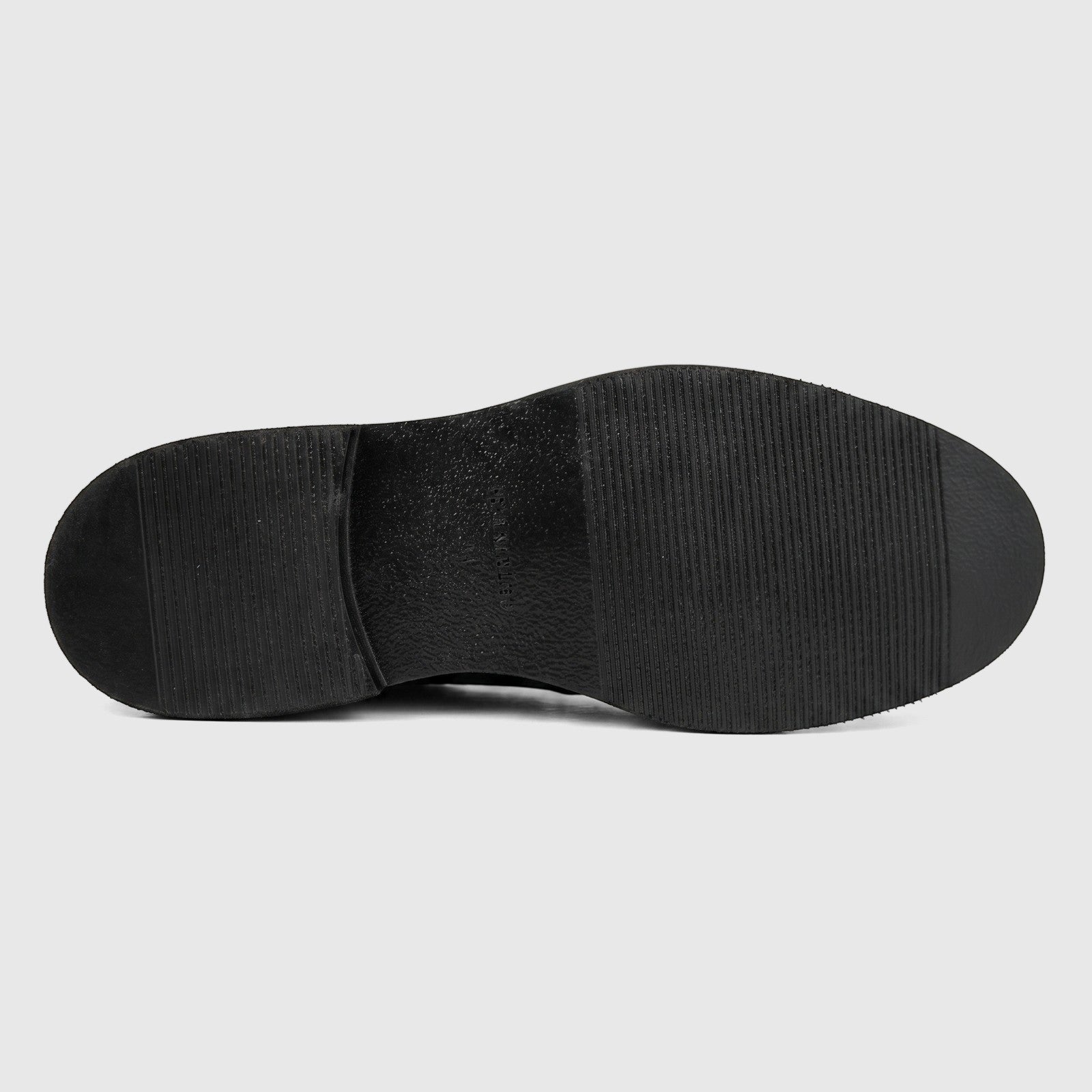 View of the black sole of a Formales men's leather slip-on shoe, featuring a textured grip pattern on a flat surface.