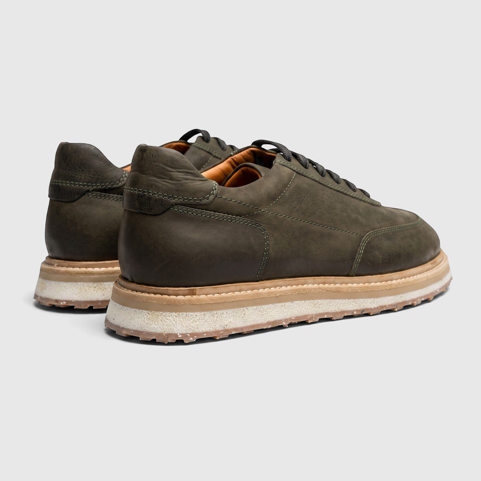 Rear-quarter view of a pair of Formales men's suede sneakers in olive green, featuring black laces and a layered sole.