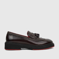 Dark brown leather unisex loafer with a chunky black sole, red trim, brogue detailing, and tassels, shown from a side view.