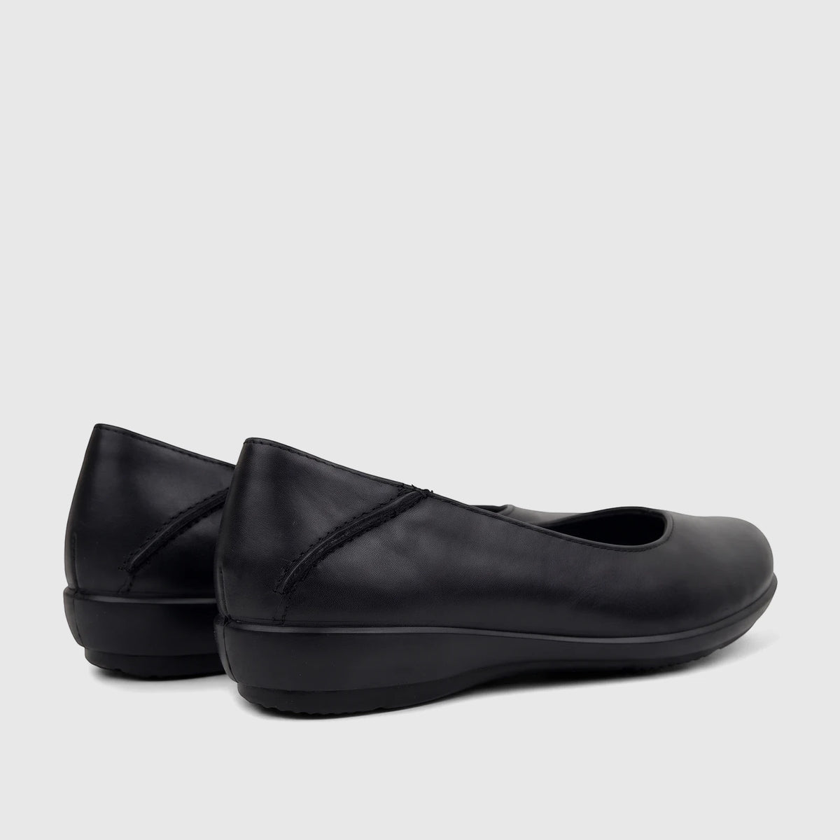 A pair of Hotter Ladies Comfort Pump Birdie in black, made from smooth leather, seen from a rear-side angle on a light