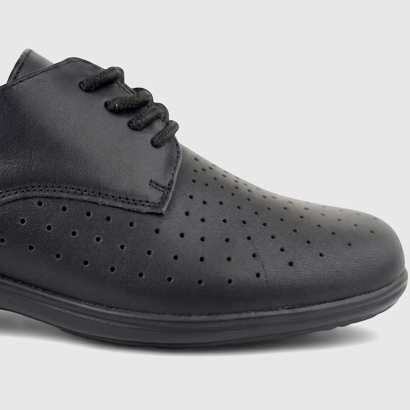 Close-up of a black perforated comfort lace-up shoe, featuring visible laces and textured material on a neutral background.