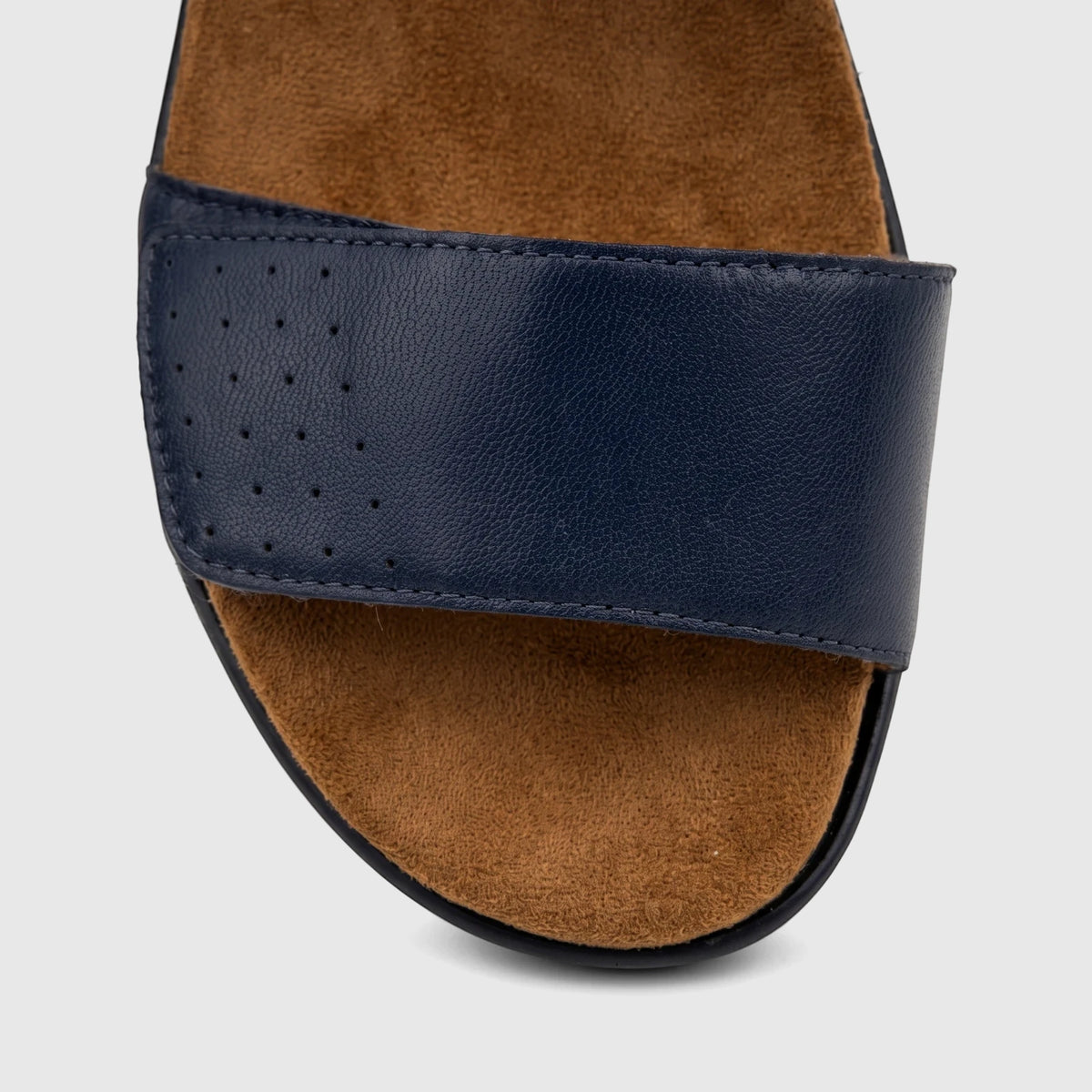 Close-up view of an HP Ladies Comfort Sandal Saria in navy blue, featuring a perforated leather strap and a brown suede-like