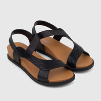 A pair of black women's comfort sandals with textured straps and a light brown wedge sole, shown from a slightly elevated