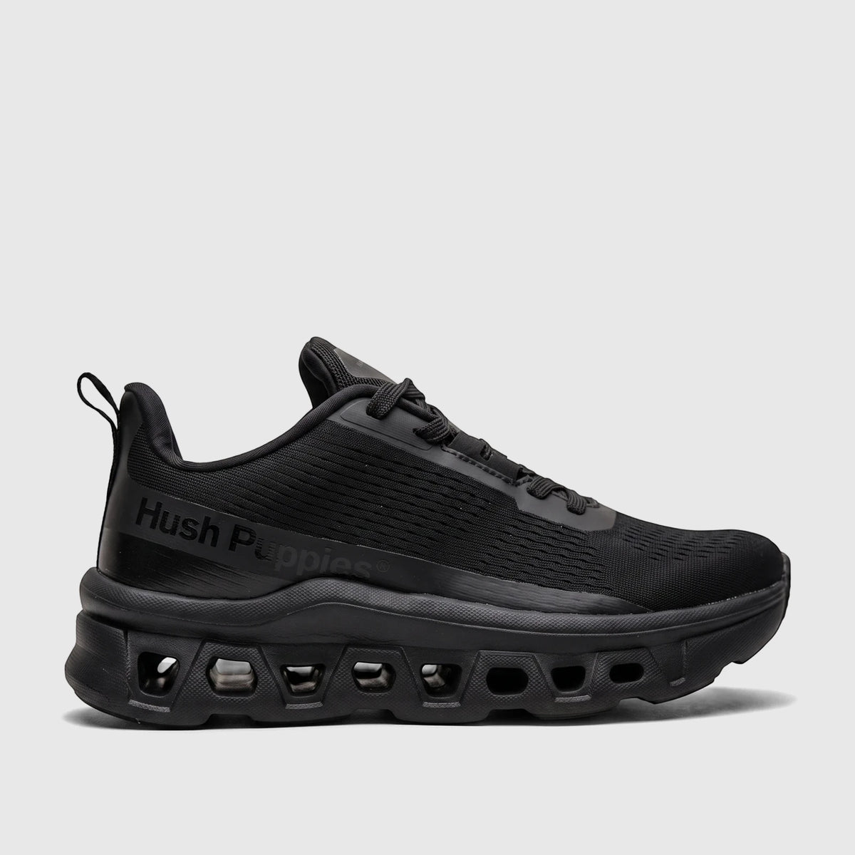 Black Hush Puppies Maxene comfort sneaker with a mesh upper and a distinctive sole design, viewed from the side.