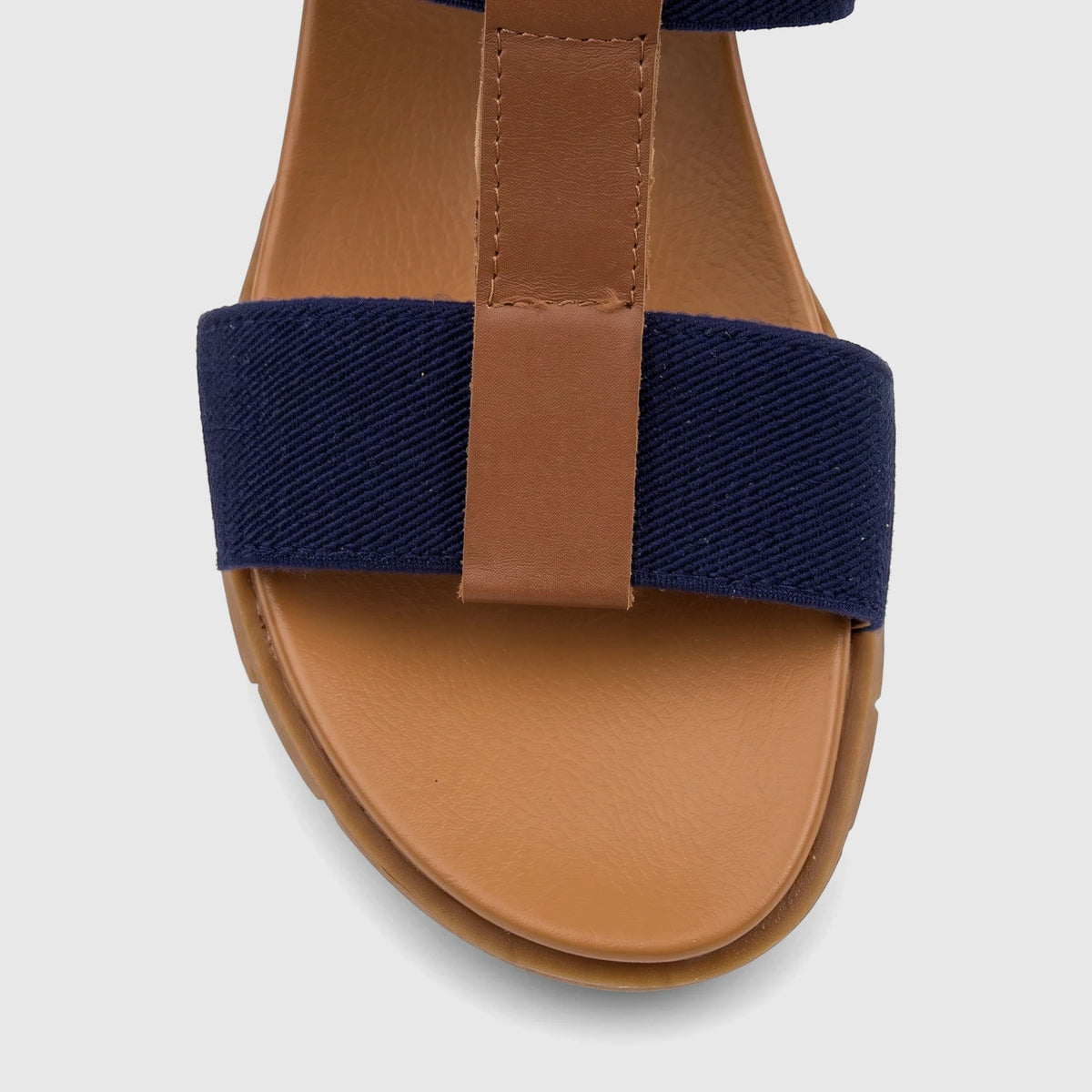 A close-up view of an HP Ladies Comfort Wedge Sandal in navy blue and brown, featuring a wide fabric strap and a