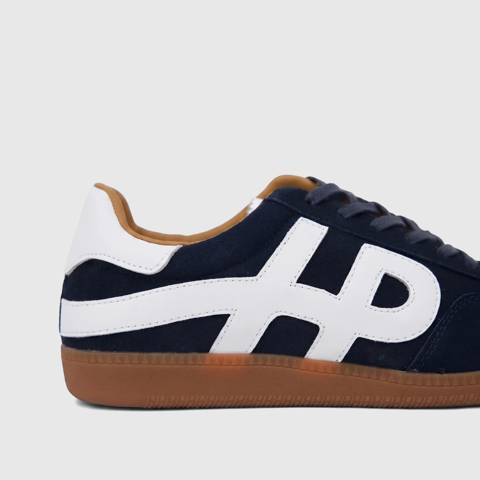 HP Men's Comfort Leather Sneaker Freddy in navy blue with white details and a gum sole, shown in a side profile view.