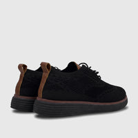 Men's black flyknit comfort sneakers with brown heel accents and a thick ribbed sole, viewed from a rear-quarter angle.