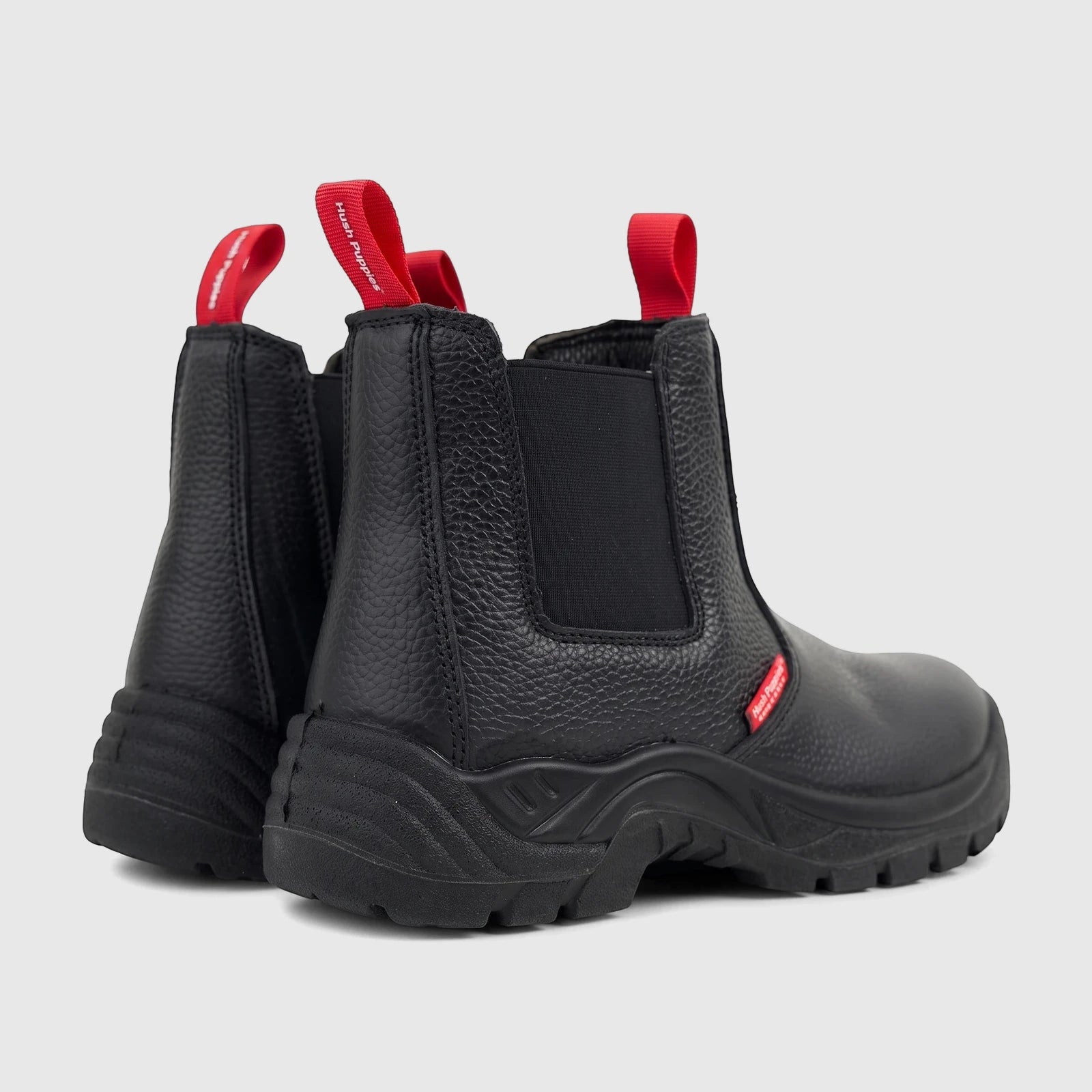 Black Hush Puppies Boulder steel toe safety boots, showcasing pebbled leather and red pull tabs from a rear-right view.