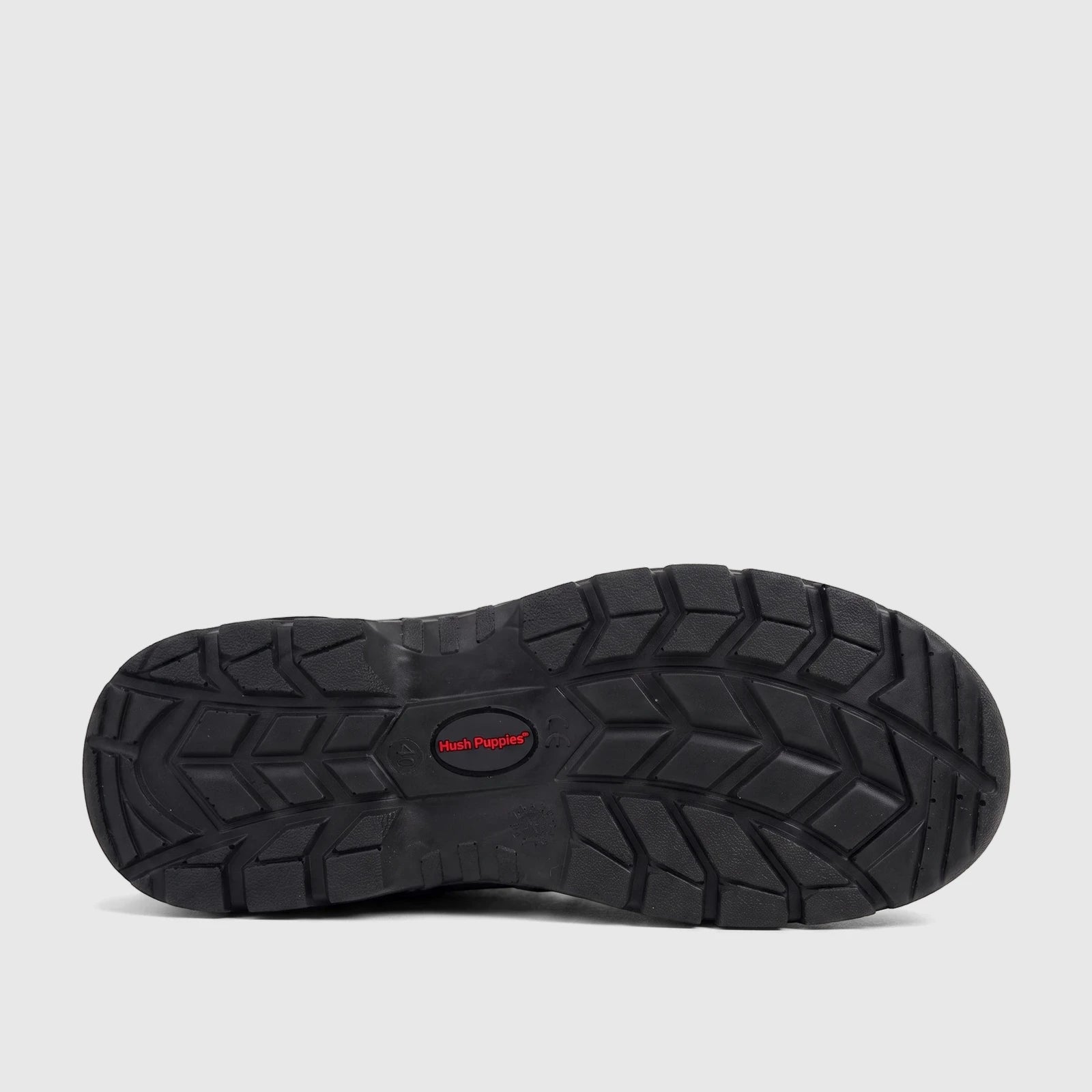 Black Hush Puppies Boulder steel toe safety boot sole with prominent deep tread pattern and red logo, viewed from below.