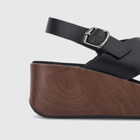 Close-up of a black Hush Puppies Jemma comfort wedge sandal with criss-cross straps and a dark brown wooden-look platform
