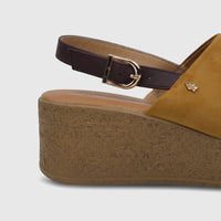 Close-up of a yellow Hush Puppies Soft Style ladies comfort wedge sandal with a brown strap and gold buckle.