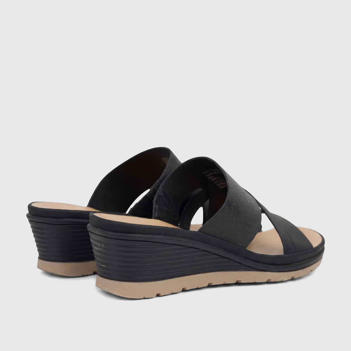 Black Hush Puppies Soft Style Posha wedge sandals with textured straps and tan soles, viewed from a rear-quarter angle.