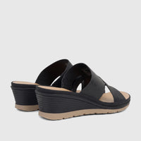 Black Hush Puppies Soft Style Posha wedge sandals with textured straps and tan soles, viewed from a rear-quarter angle.