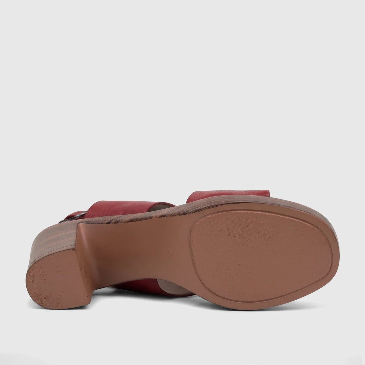 Bottom view of a burnished dark red Hush Puppies Soft Style ladies block heel sandal with a wood-grain patterned heel.