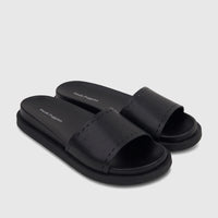 A pair of black Hush Puppies Reya comfort slides with visible stitching on the strap and the brand's logo printed on the