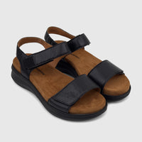 Pair of black Hush Puppies Saria comfort wedge sandals for ladies, featuring adjustable straps and tan footbeds.