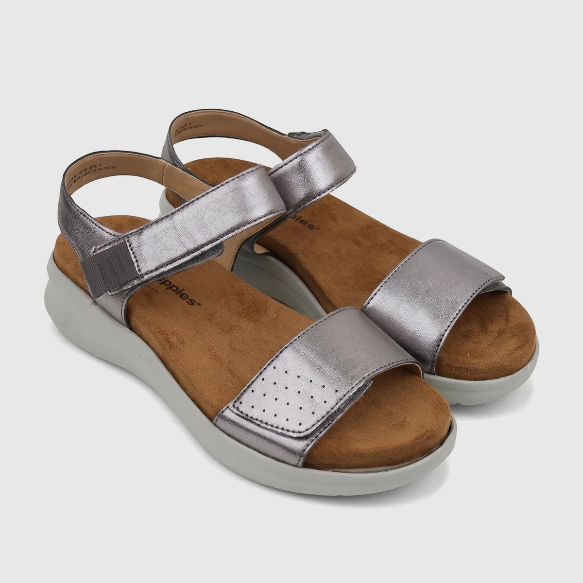 Pair of metallic silver Hush Puppies Saria comfort sandals for ladies, featuring perforated straps and wedge soles.