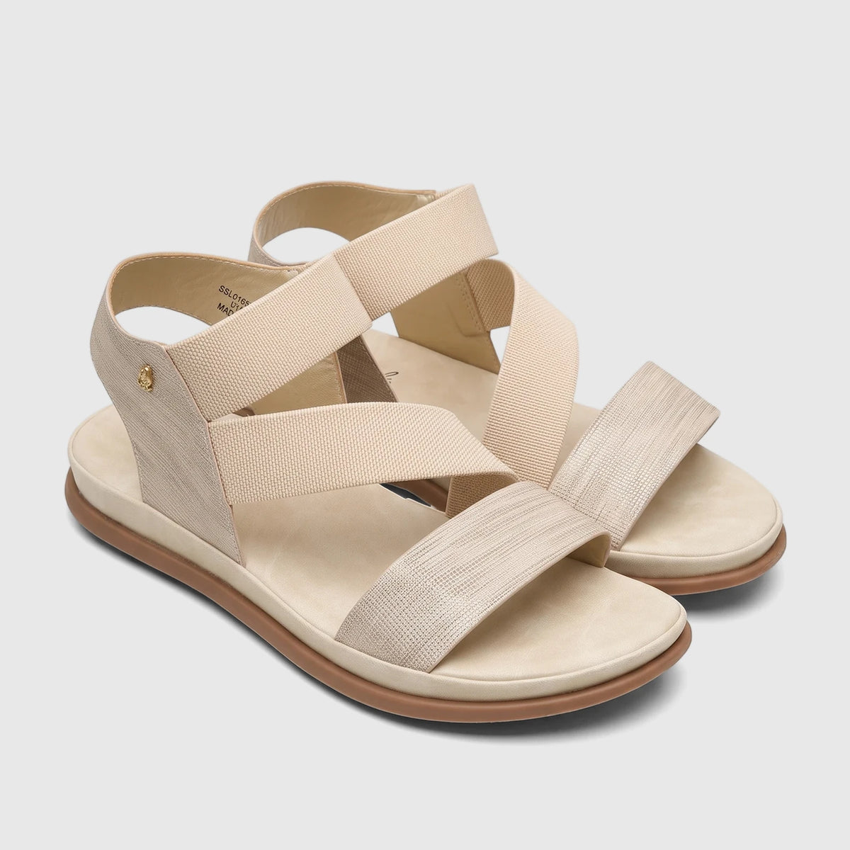 A pair of Hush Puppies Soft Style Ladies Comfort Sandal Indy in light gold, featuring elastic and textured straps with a