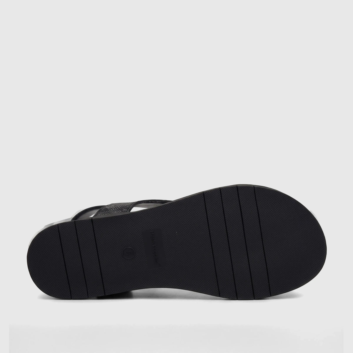 Black Hush Puppies Zaira comfort sandal with a textured sole, captured from a low-angle perspective showing the underside.