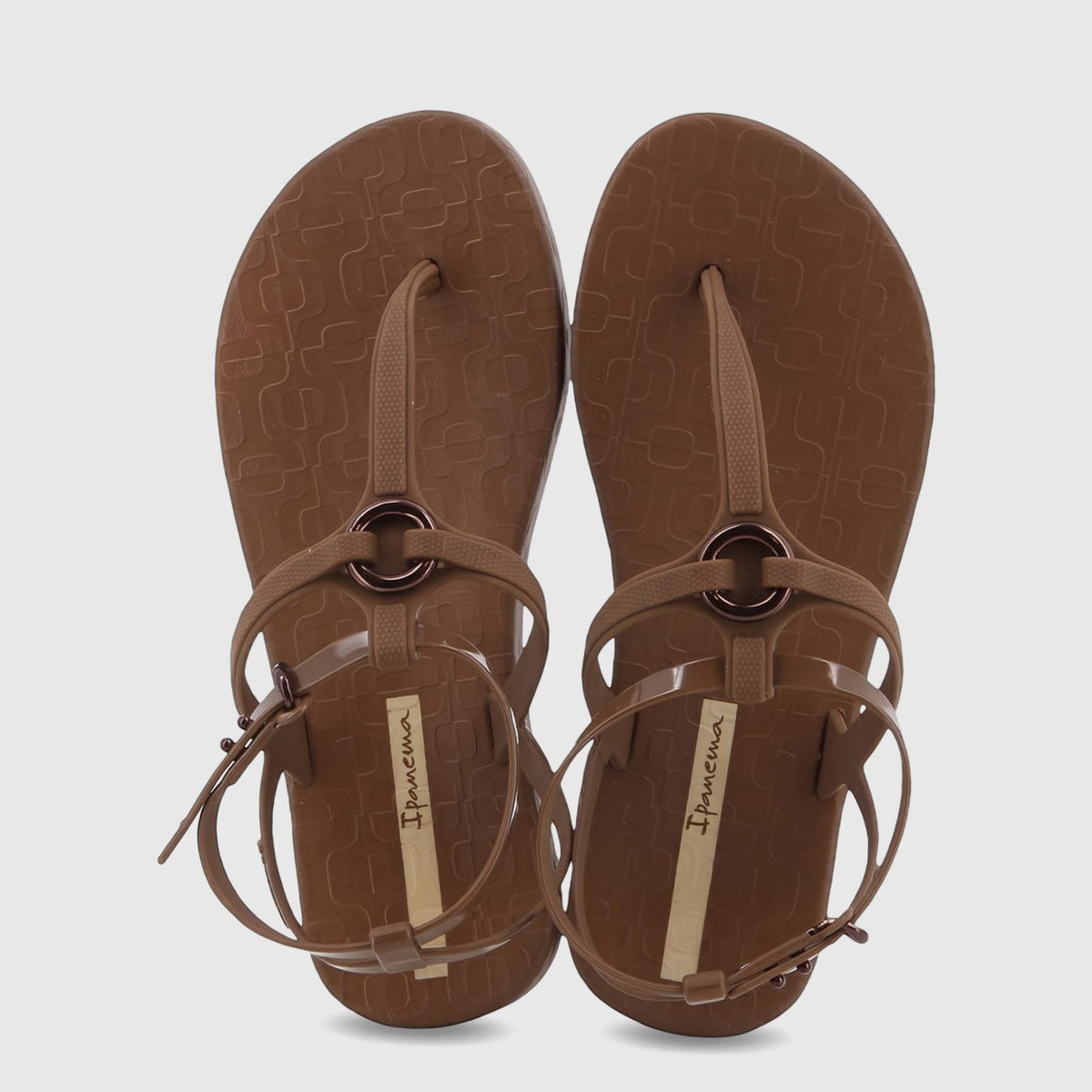 Pair of Ipanema Atena thong sandals in brown, featuring an ankle strap with a buckle and a circular metal detail, viewed