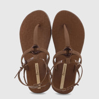 Pair of Ipanema Atena thong sandals in brown, featuring an ankle strap with a buckle and a circular metal detail, viewed