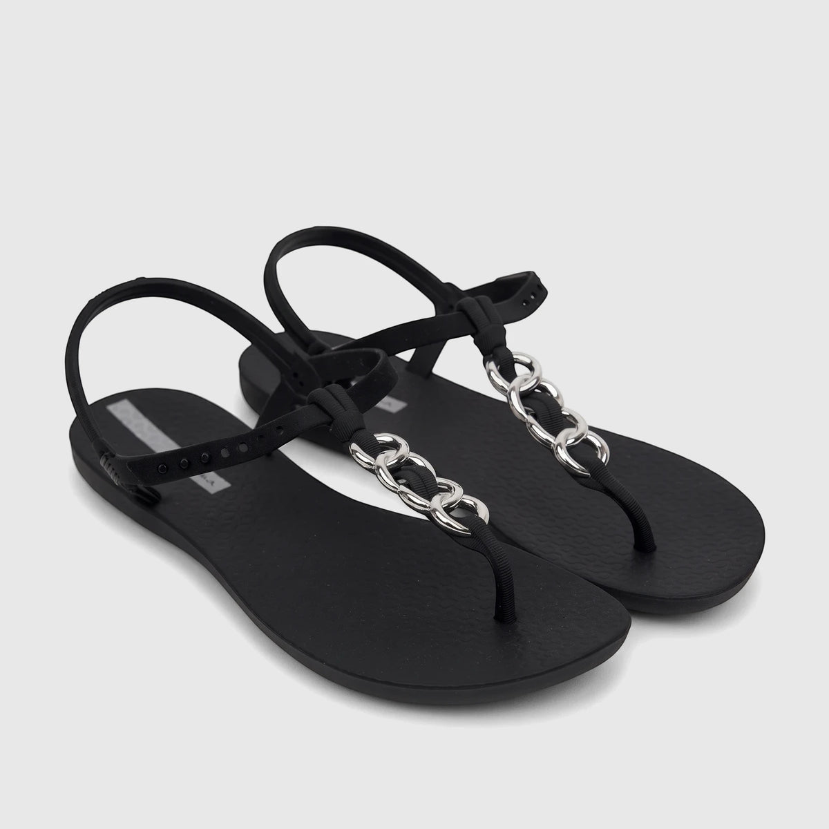 A pair of black Ipanema Class Lizz sandals with silver chain-link details and an adjustable ankle strap, viewed from an