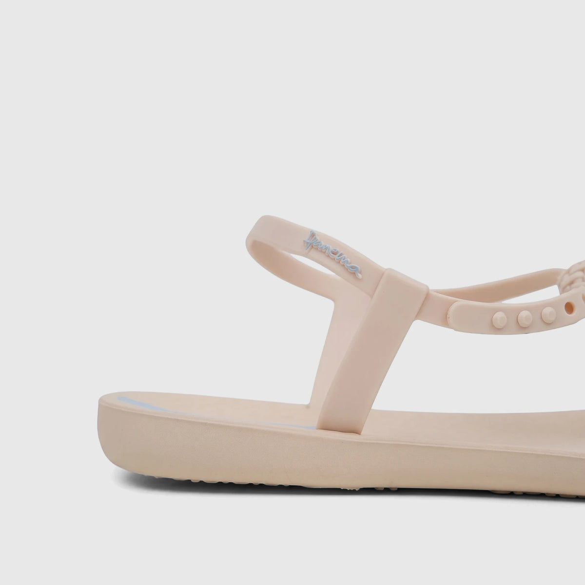 Close-up side view of a single beige Ipanema Class Posh sandal, showcasing the adjustable strap with the blue logo.
