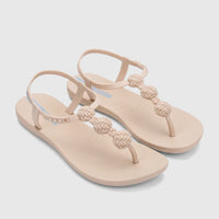 Pair of beige Ipanema Class Posh T-strap sandals with decorative woven-look spheres on a light surface, viewed from an